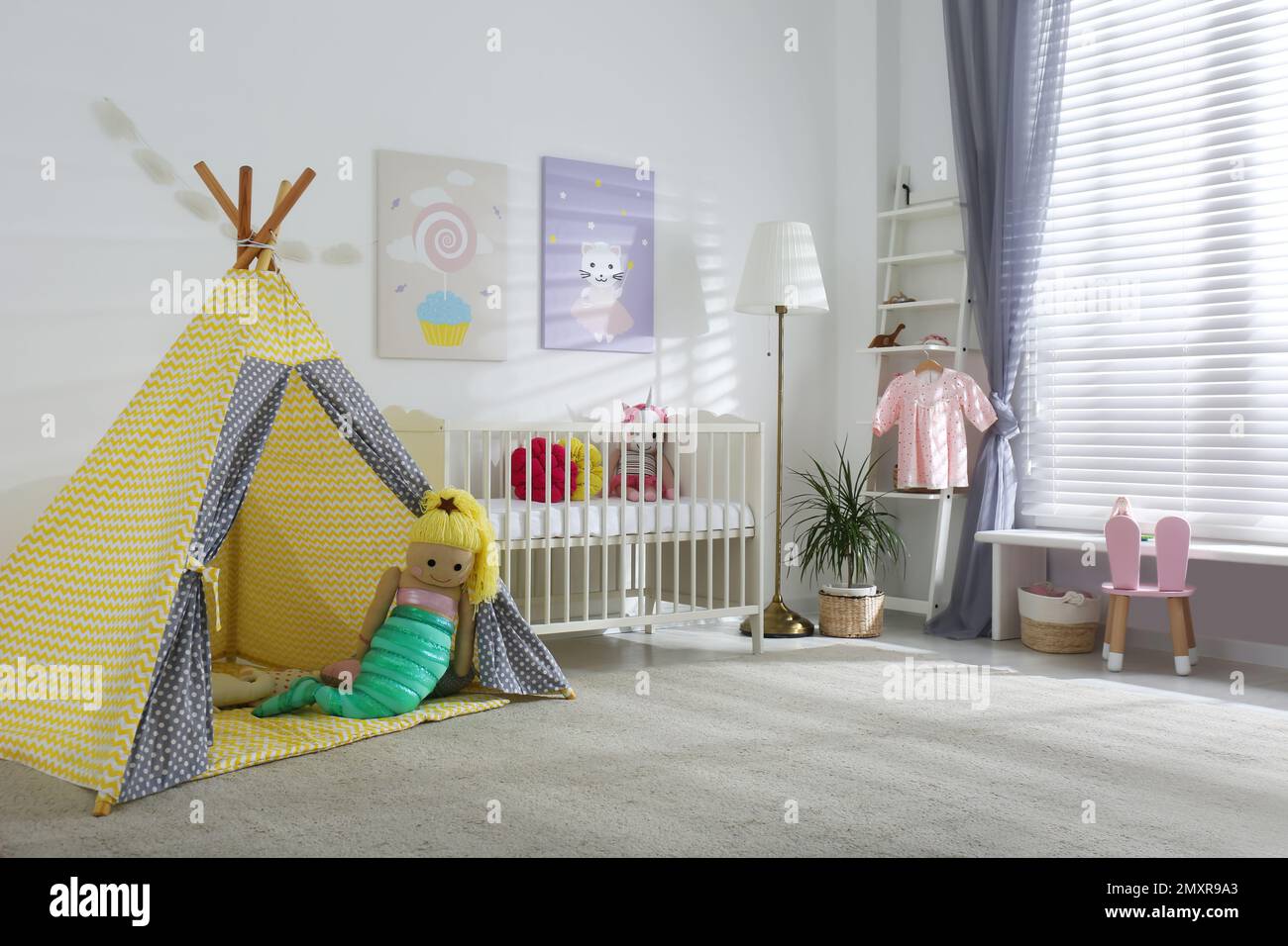 Innenausstattung des Babyzimmers mit niedlichen Postern, Spielzelt und komfortablem Kinderbett Stockfoto