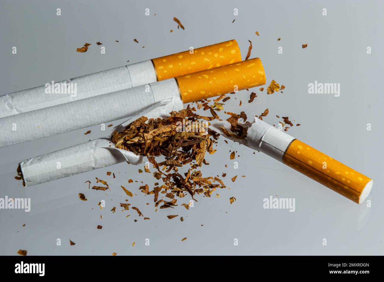 Gebrochene Zigarettenfliege in der Luft auf einem hellen Hintergrund. Konzeption der Bekämpfung des Rauchens. Stockfoto