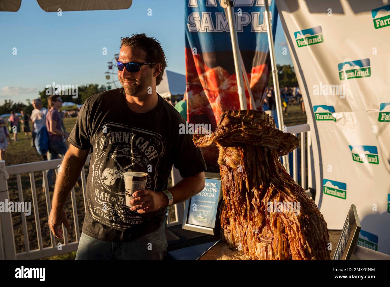 A festival-goer stops by the Farmland Bacon Club booth for a one-of-kind photo op with a custom-made Chris Stapleton bacon sculpture on Saturday, Sept. 10, 2016, at LouFest in St. Louis. (Photo by Whitney Curtis/Invision for Farmland/AP Images) Stockfoto