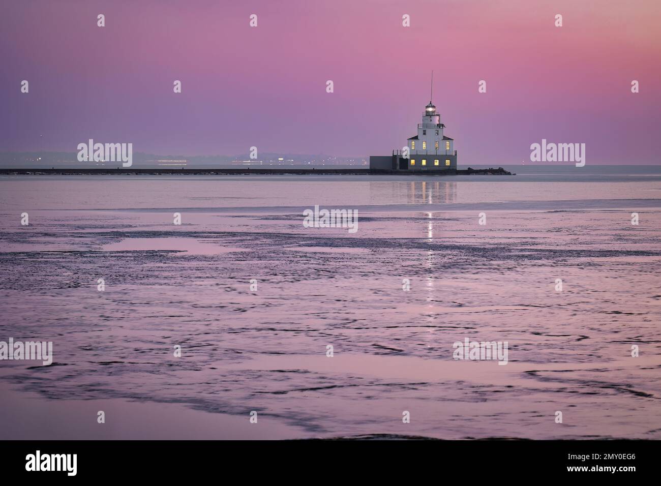 Ein farbenfroher Sonnenaufgang im Januar hinter dem Leuchtturm des Lake Michigan am gefrorenen Hafen von Manitowoc, Wisconsin. Stockfoto