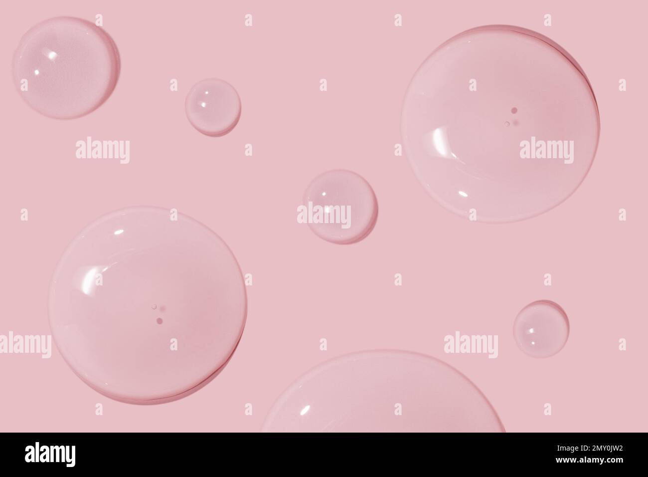 Große Tropfen kosmetisches Serum, Flüssigkeit, Wasser, Gel auf pinkfarbenem Hintergrund Stockfoto
