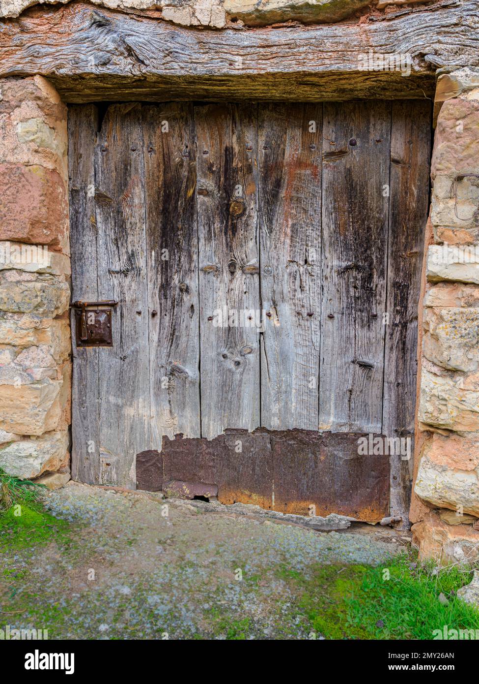 Alte Holztür mit Holzlintel, geschlossenem Metallschloss und unterem Teil mit Blech Stockfoto