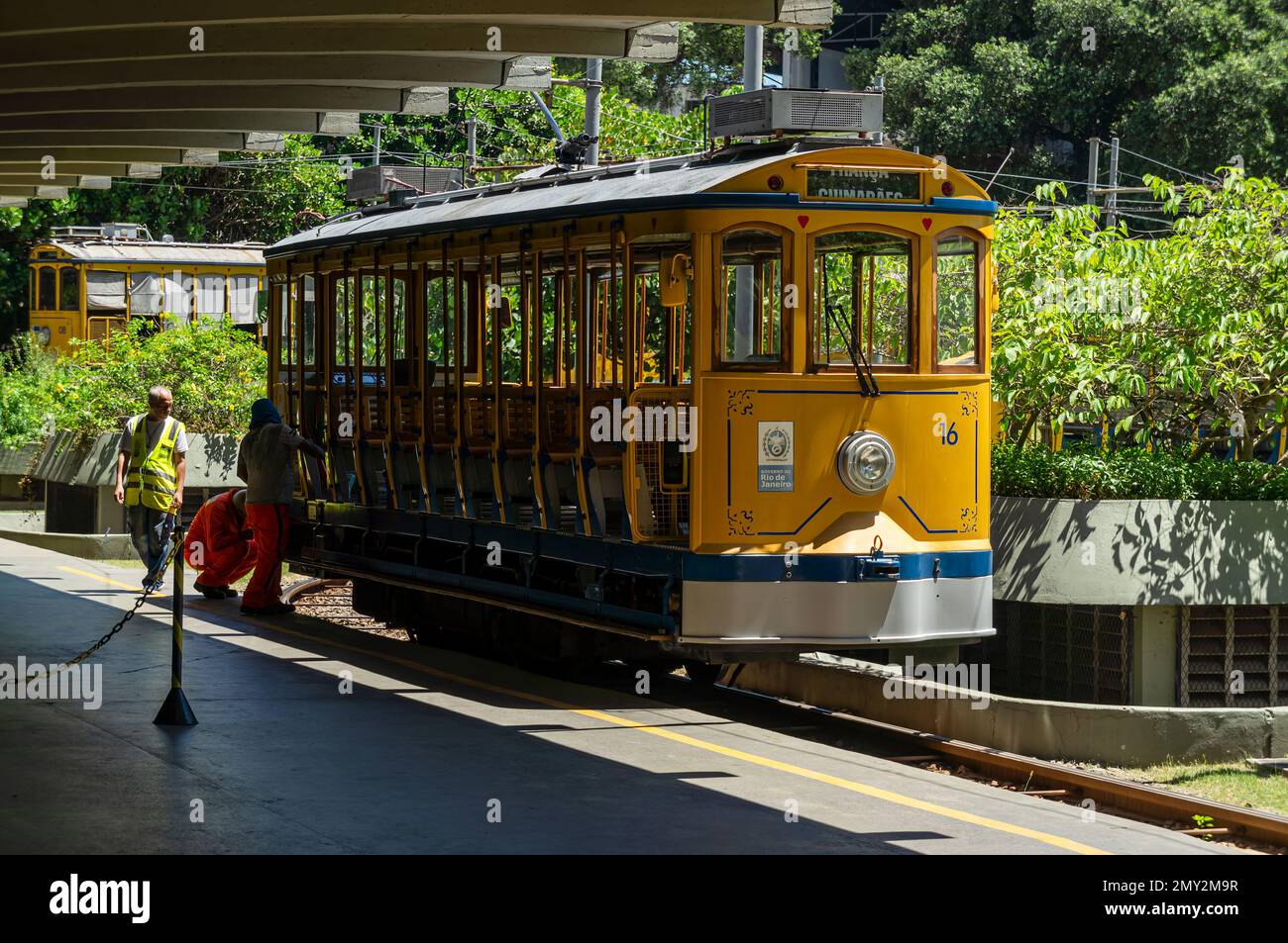 Die gelbe Straßenbahn Nr. 16 von Santa Teresa wird von Bahnhofsangestellten überprüft, bevor die Passagiere an Bord gehen und in Richtung Largo dos Guimaraes fahren. Stockfoto