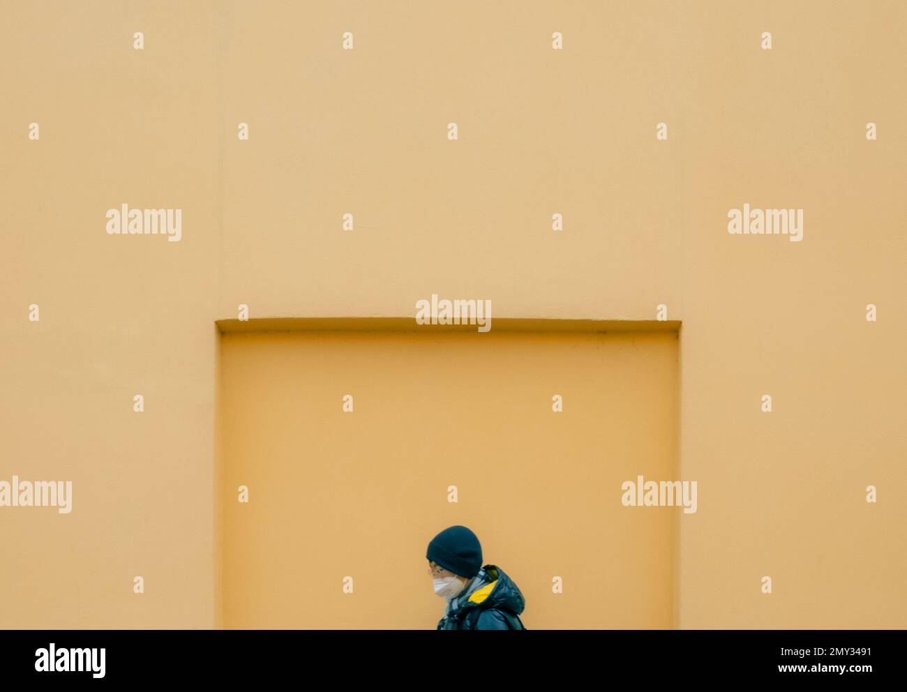 Eine Person, die vor einer orangefarbenen Mauer geht Stockfoto