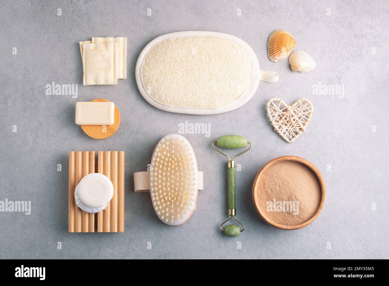 Trockener Ton, Wattepads, Waschlappen, Massagebürste, Gesichtswalze, Seife und Naturdekor auf Steintisch. Stockfoto