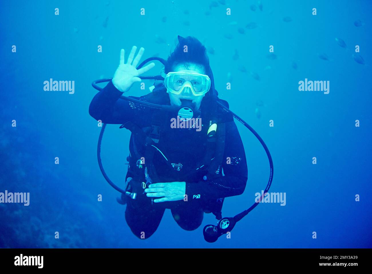 Eine Taucherin unter Wasser, die Hand schüttelt und auf die Kamera starrt Stockfoto