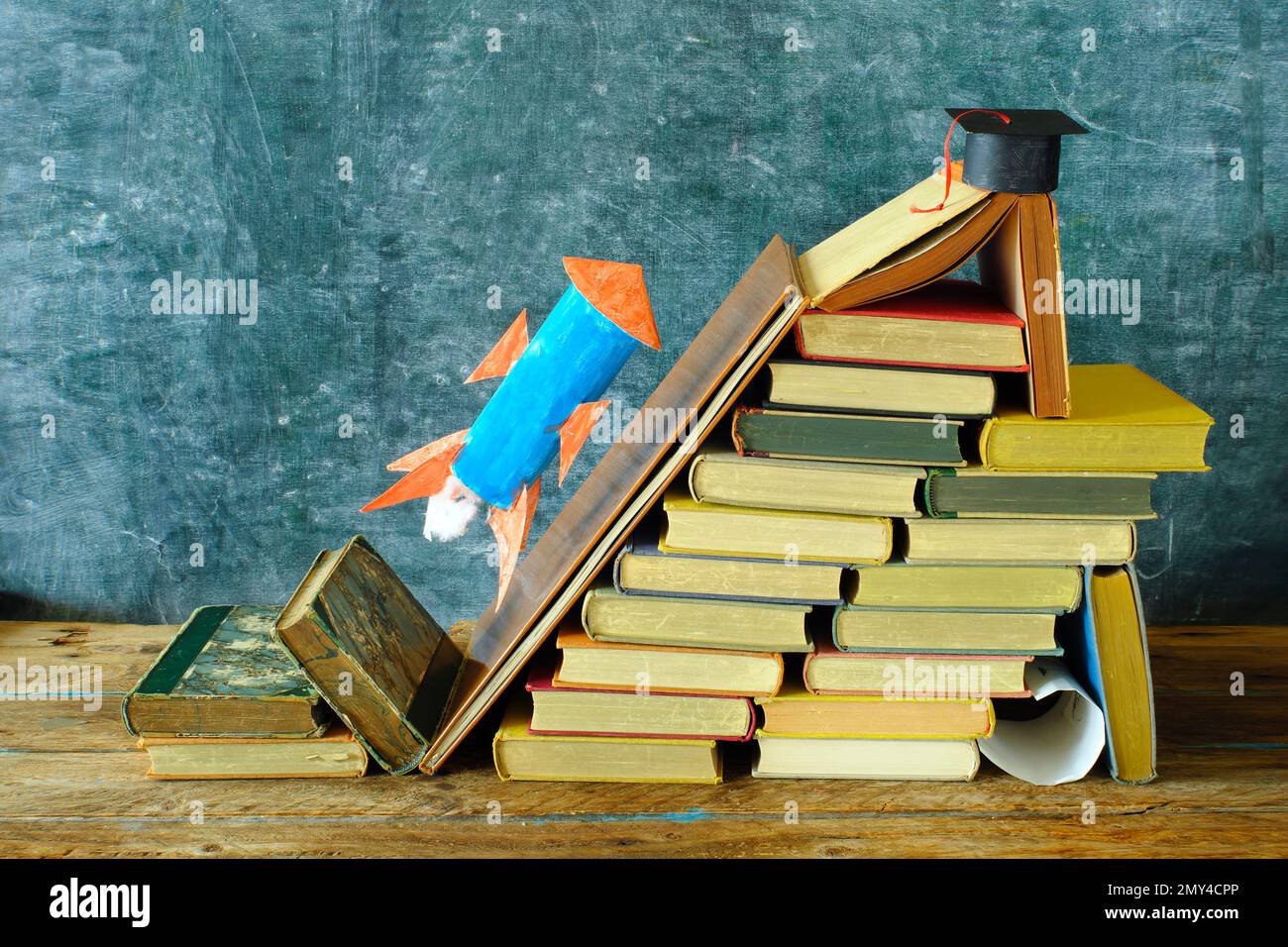 Stapel von Büchern mit Raketenstart auf der Tafel. Lernen, Bildung ist Macht, persönliche Entwicklung, Leiter des Erfolgs und zurück Stockfoto