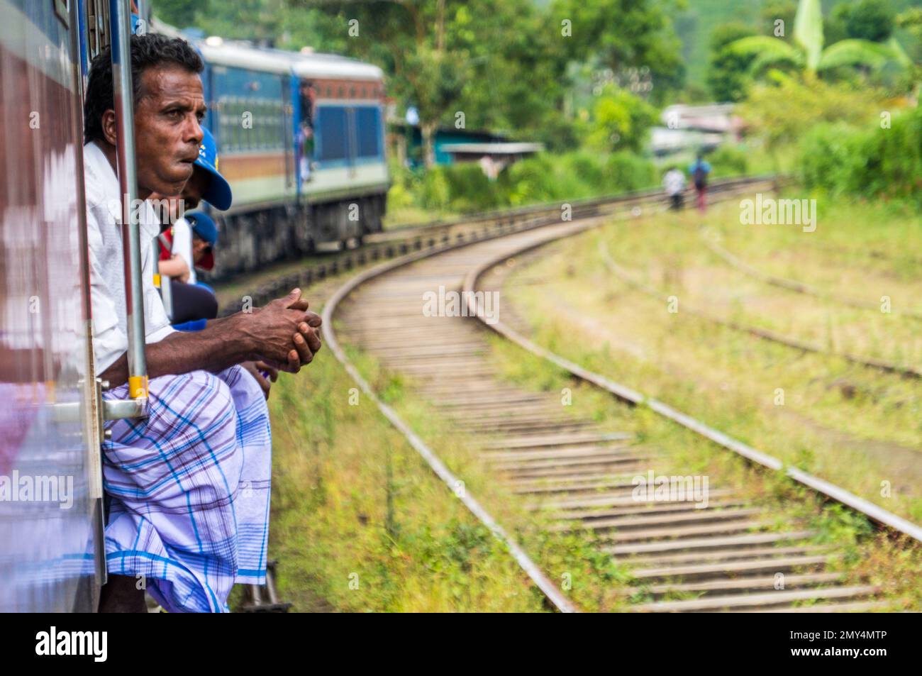 Ein Mann, der vom Zug durch das Hill Country von Kandy bis Ella pensiv blickt. Sri Lanka Stockfoto