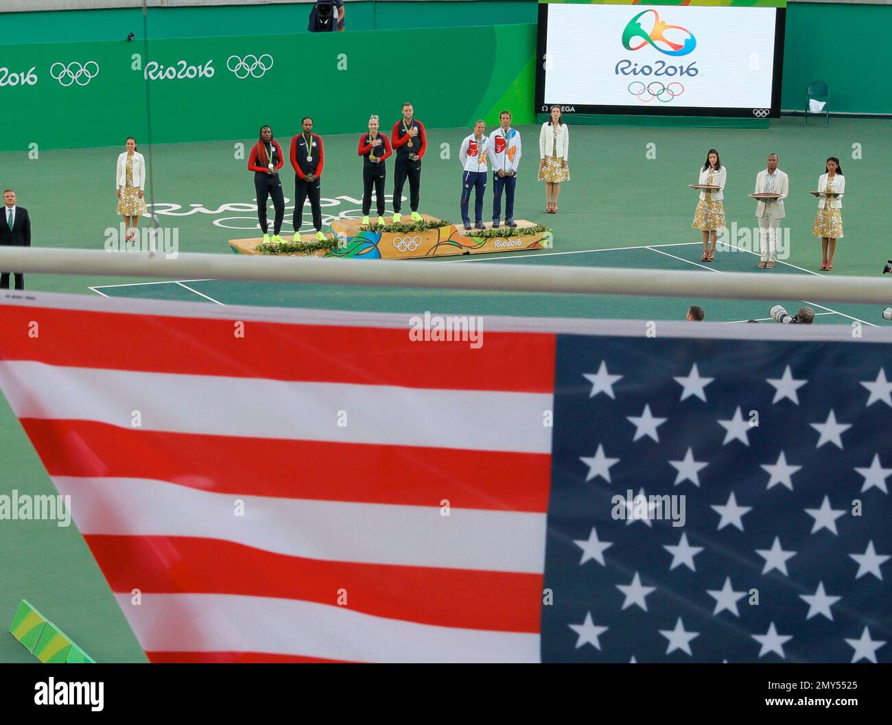 The flags of the United States and the Czech Republic are raised during the medals ceremony of the mixed doubles tennis competition at the 2016 Summer Olympics in Rio de Janeiro, Brazil, Sunday, Aug. 14, 2016. Bethanie Mattek-Sands, of the United States, and Jack Sock, center on podium, won gold, Venus Williams and Rajeev Ram, of the United States, left, won silver and the Czech Republic's Lucie Hradecka and Radek Stepanek, right, won bronze. (AP Photo/Vadim Ghirda) Stockfoto