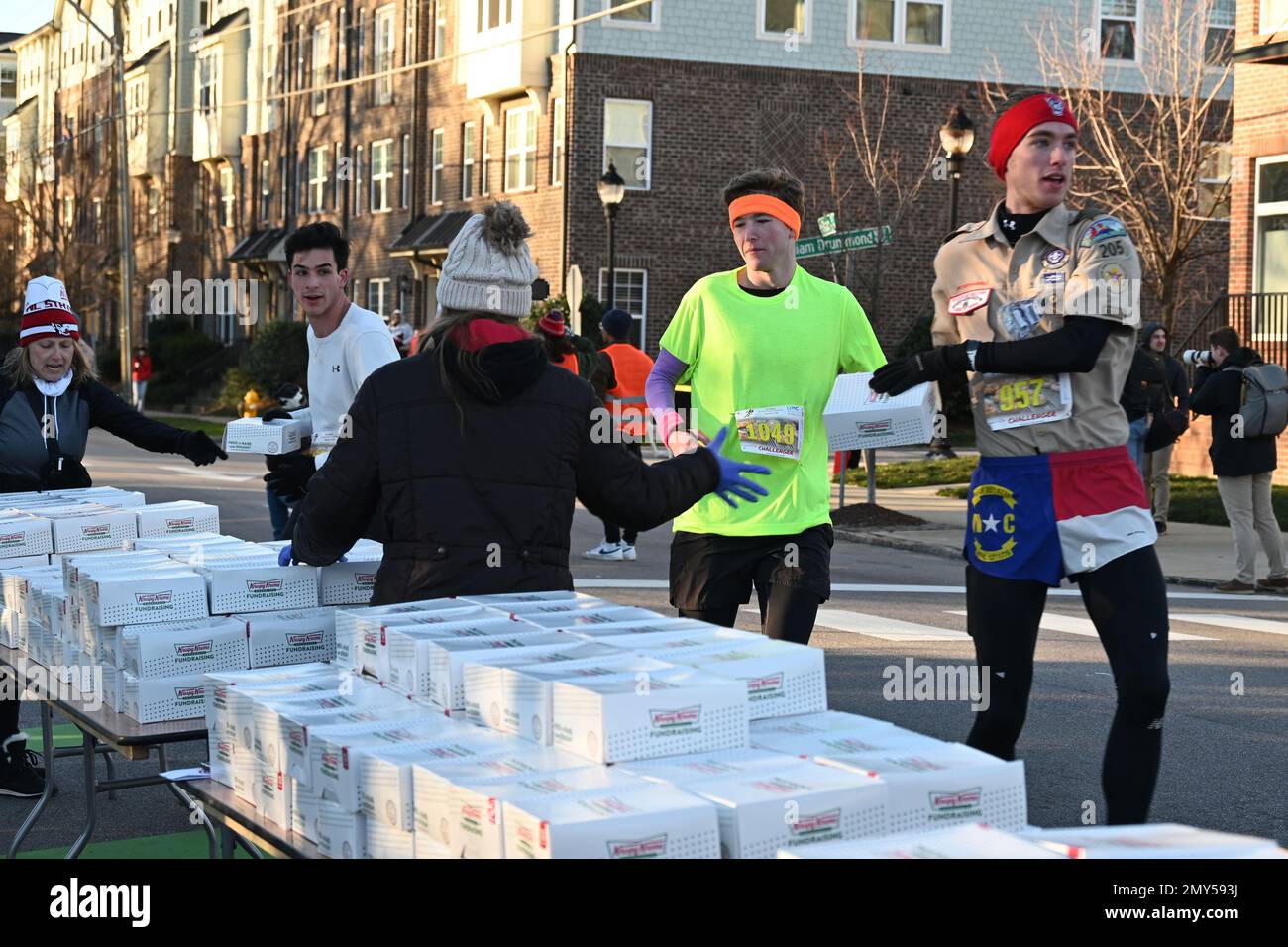 Raleigh, NC, USA, 4. Februar 2023, schnappen sich Läufer Kisten Krispy Kreme Doughnuts auf halber Strecke eines 5 km langen Sprints vom Campus der North Carolina State University. Die alljährliche Krispy Kreme Challenge wurde 2004 unter Freunden zum ersten Mal als „Mut“ geführt und wurde schnell zu einer Benefizveranstaltung für das Kinderkrankenhaus des UNC. Der Kursrekord von 28:29 wurde 2020 mit einem Tempo von 5:41/Meile gesetzt, einschließlich Zeit zum Essen von Donuts. Bei landesweiter Exposition lautet das Motto „2.400 Kalorien, 12 Donuts, 5 Meilen, 1 Stunde“. Credit D Guest Smith / Alamy Live News Stockfoto