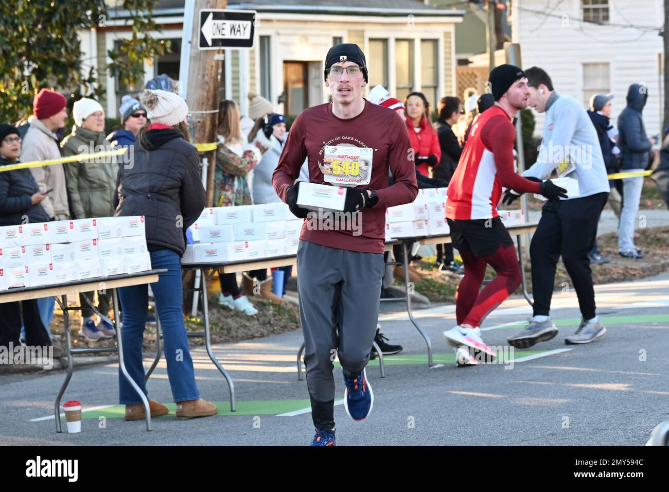 Raleigh, NC, USA, 4. Februar 2023, schnappen sich Läufer Kisten Krispy Kreme Doughnuts auf halber Strecke eines 5 km langen Sprints vom Campus der North Carolina State University. Die alljährliche Krispy Kreme Challenge wurde 2004 unter Freunden zum ersten Mal als „Mut“ geführt und wurde schnell zu einer Benefizveranstaltung für das Kinderkrankenhaus des UNC. Der Kursrekord von 28:29 wurde 2020 mit einem Tempo von 5:41/Meile gesetzt, einschließlich Zeit zum Essen von Donuts. Bei landesweiter Exposition lautet das Motto „2.400 Kalorien, 12 Donuts, 5 Meilen, 1 Stunde“. Credit D Guest Smith / Alamy Live News Stockfoto
