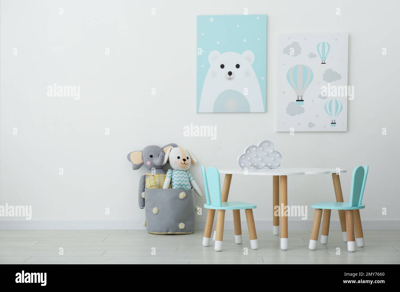 Bezaubernde Wandgemälde, Tisch und Stühle mit Hasenohren im Kinderzimmer Stockfoto