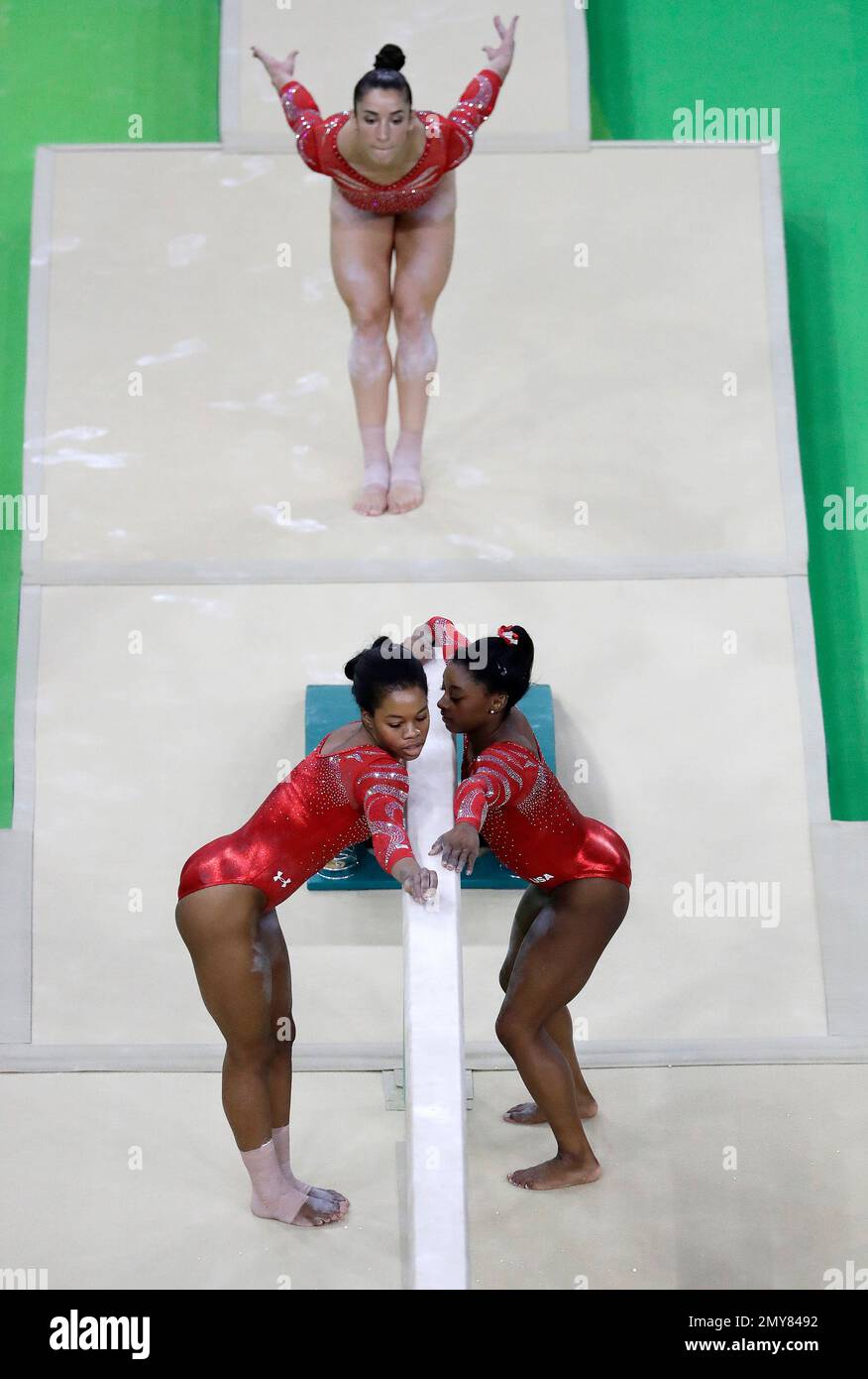United States' Gabrielle Douglas, bottom left, and Simone Biles, bottom right, measure off the beam as Alexandra Raisman trains before getting on the beam ahead of the 2016 Summer Olympics in Rio de Janeiro, Brazil, Thursday, Aug. 4, 2016. (AP Photo/Julio Cortez) Stockfoto