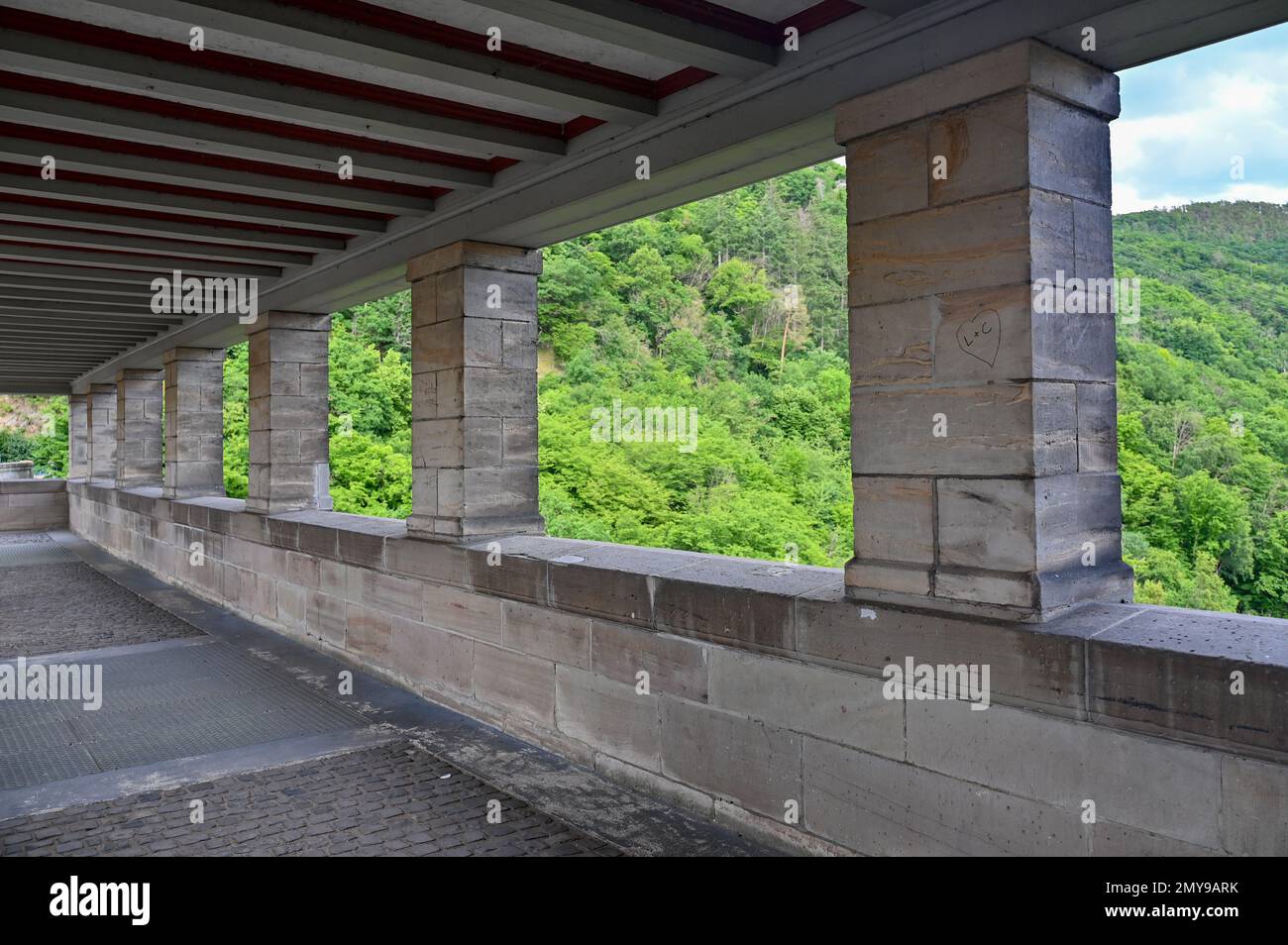 Säulen auf dem Fußgängerweg am Damm Edersee in Deutschland mit Blick auf den grünen Wald Stockfoto