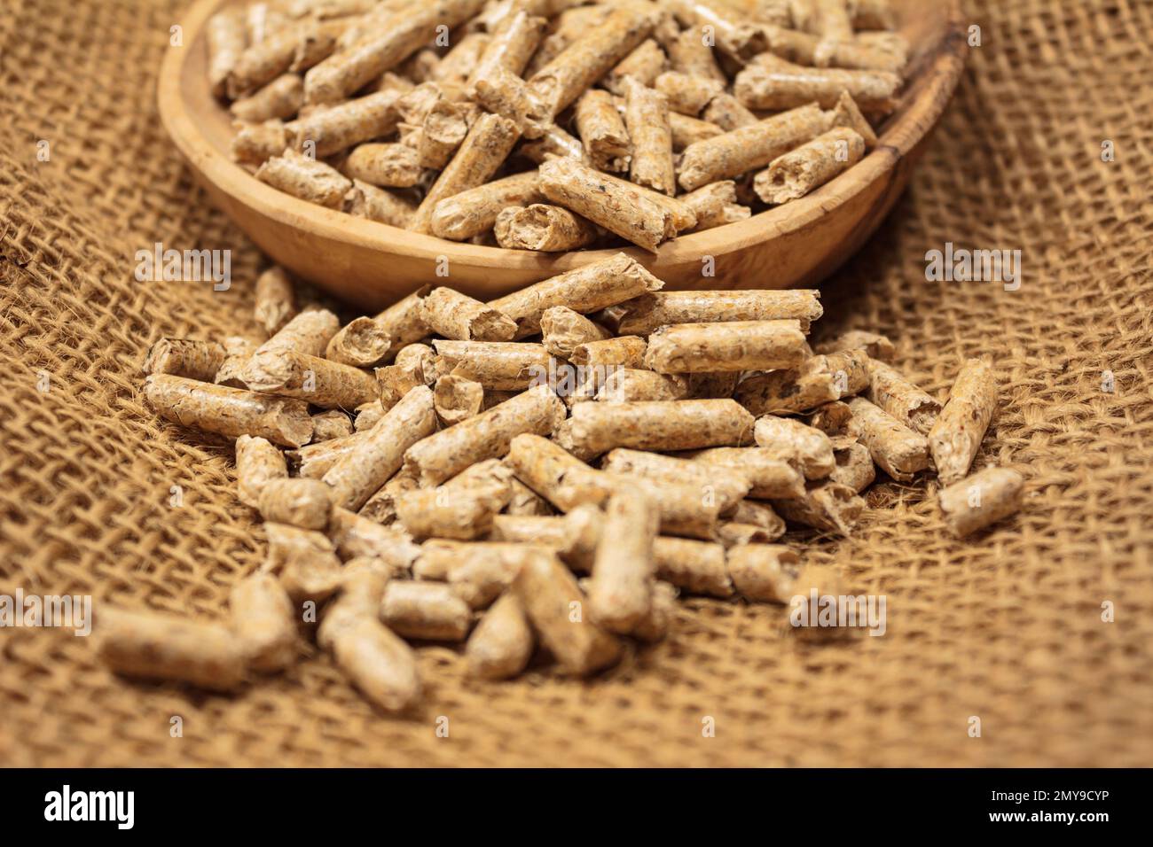 Holzpelletstapel in und vor einer Holzschüssel ein Jutetuch Stockfoto