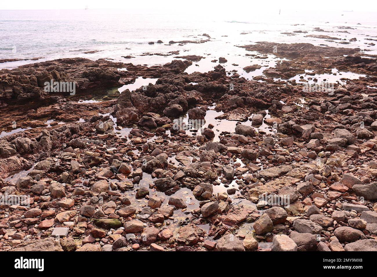 Küstenlinie mit dem Meer, das durch die unregelmäßigen Felsen eindringt Stockfoto