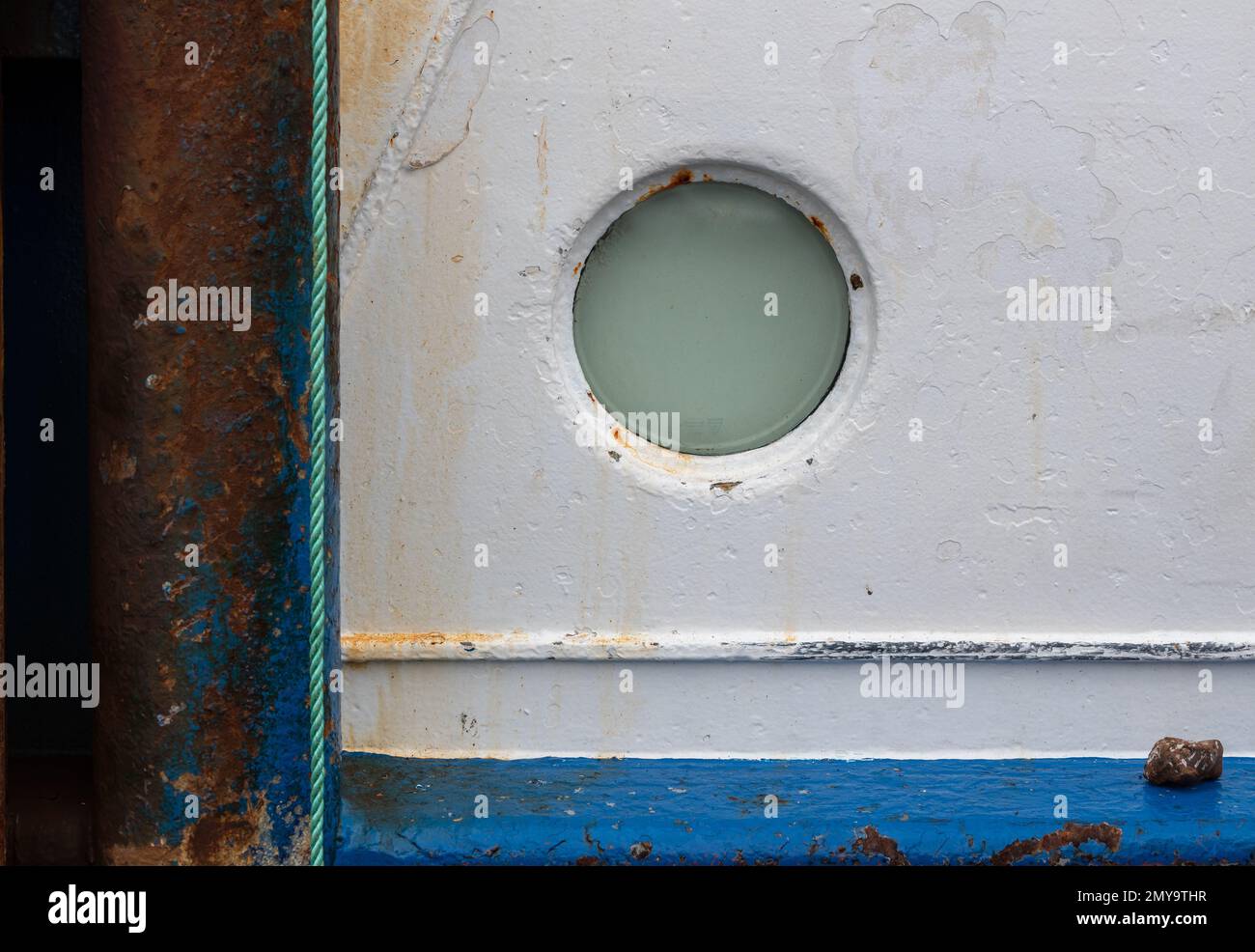 Fenster oder Backbordloch an der Seite eines Fischerboots. Mischung aus Kreisen und Linien mit Verwitterung und Rost, die die Textur erhöhen. Stockfoto