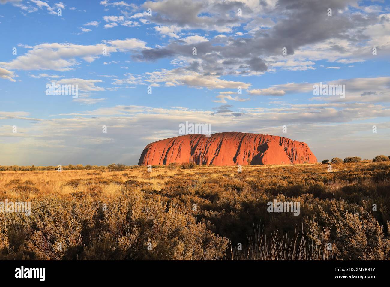 478 Uhr am späten Nachmittag Blick auf den Uluru Ayers Rock bei warmem Sonnenlicht und einem überwiegend bewölkten Himmel. NT-Australien. Stockfoto