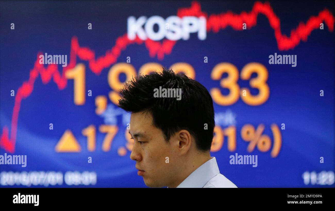 A currency trader looks at the monitors near a screen showing the Korea Composite Stock Price Index (KOSPI) at the foreign exchange dealing room in Seoul, South Korea, Friday, July 1, 2016. Asian shares mostly rose Friday with investors remaining in a buying mood amid low interest rates and after world markets recovered their losses from Britain's vote to leave the European Union a week ago. (AP Photo/Lee Jin-man) Stockfoto