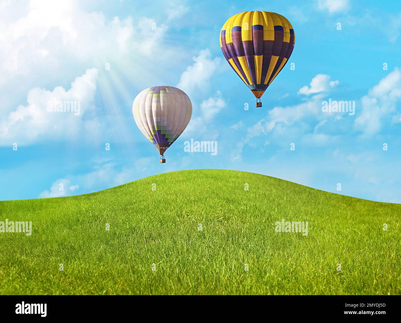 Traumwelt. Heißluftballons am Himmel mit Wolken über grüner Wiese Stockfoto
