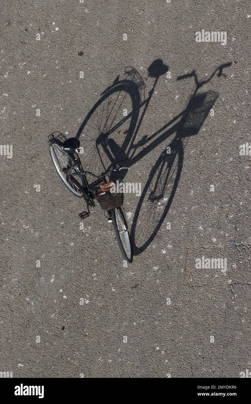 Das abendliche Sonnenlicht wirft einen langen, einzigartigen Schatten von einem Damenfahrrad, das am Kai in Zadar, Kroatien, am 2022. September geparkt ist. Stockfoto