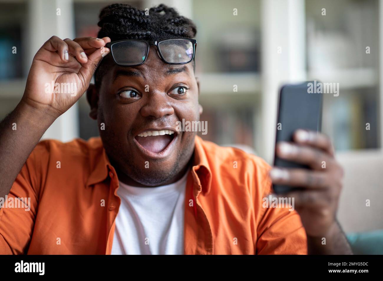 Emotionaler afrikaner ist aufgeregt, gute Nachrichten auf dem Handy zu erhalten Stockfoto