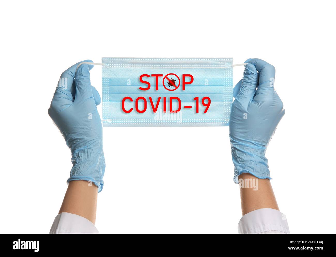 Arzt hält medizinische Maske mit Text Stop Covid-19 auf weißem Hintergrund, close seup. Schutzmaßnahmen während einer Pandemie Stockfoto