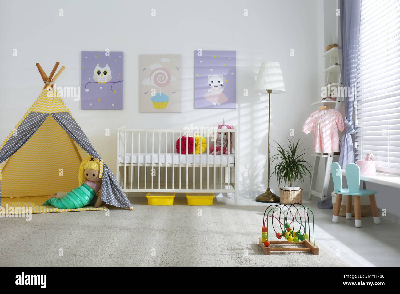 Innenausstattung des Babyzimmers mit niedlichen Postern, Spielzelt und komfortablem Kinderbett Stockfoto