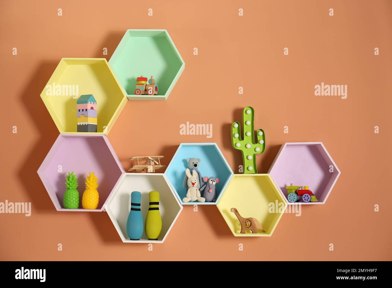 Sechseckige Regale mit Spielzeug an orangefarbenen Wänden. Innendesign Stockfoto