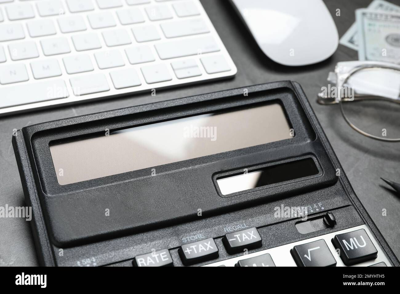 Taschenrechner und Tastatur auf dunkelgrauem Tisch, Nahaufnahme. Steuerbuchhaltung Stockfoto