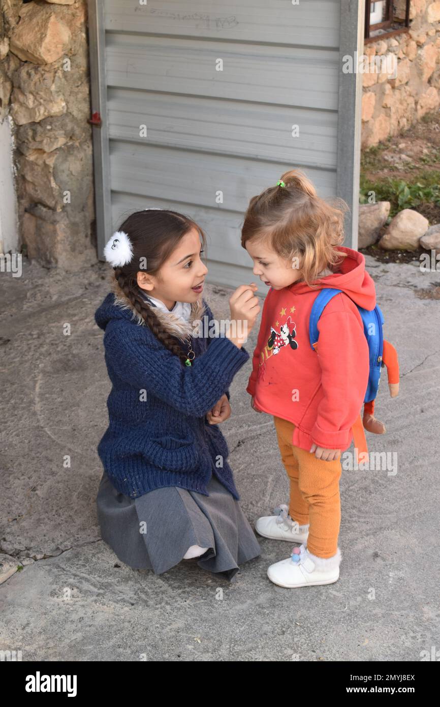 Ein Schulmädchen im Nordirak teilt Süßigkeiten mit ihrer kleinen Schwester. Stockfoto