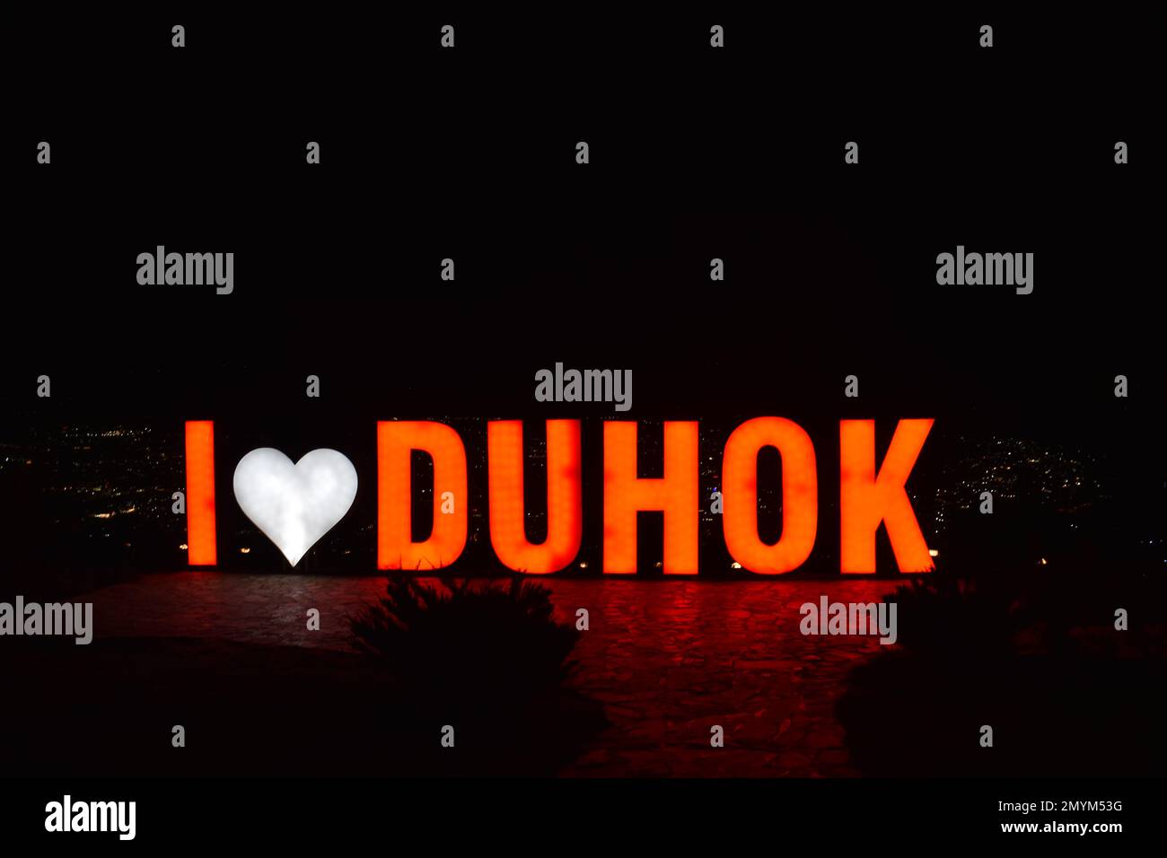 „I Love Duhok“-Schild, beleuchtet bei Nacht, auf dem Berg Zawa, mit Blick auf die Stadt Duhok, Irak. Stockfoto