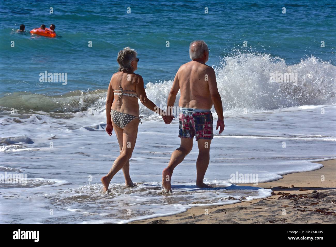 Altes Paar, das Hand in Hand am Strand läuft, Andalusien, Spanien, Europa Stockfoto