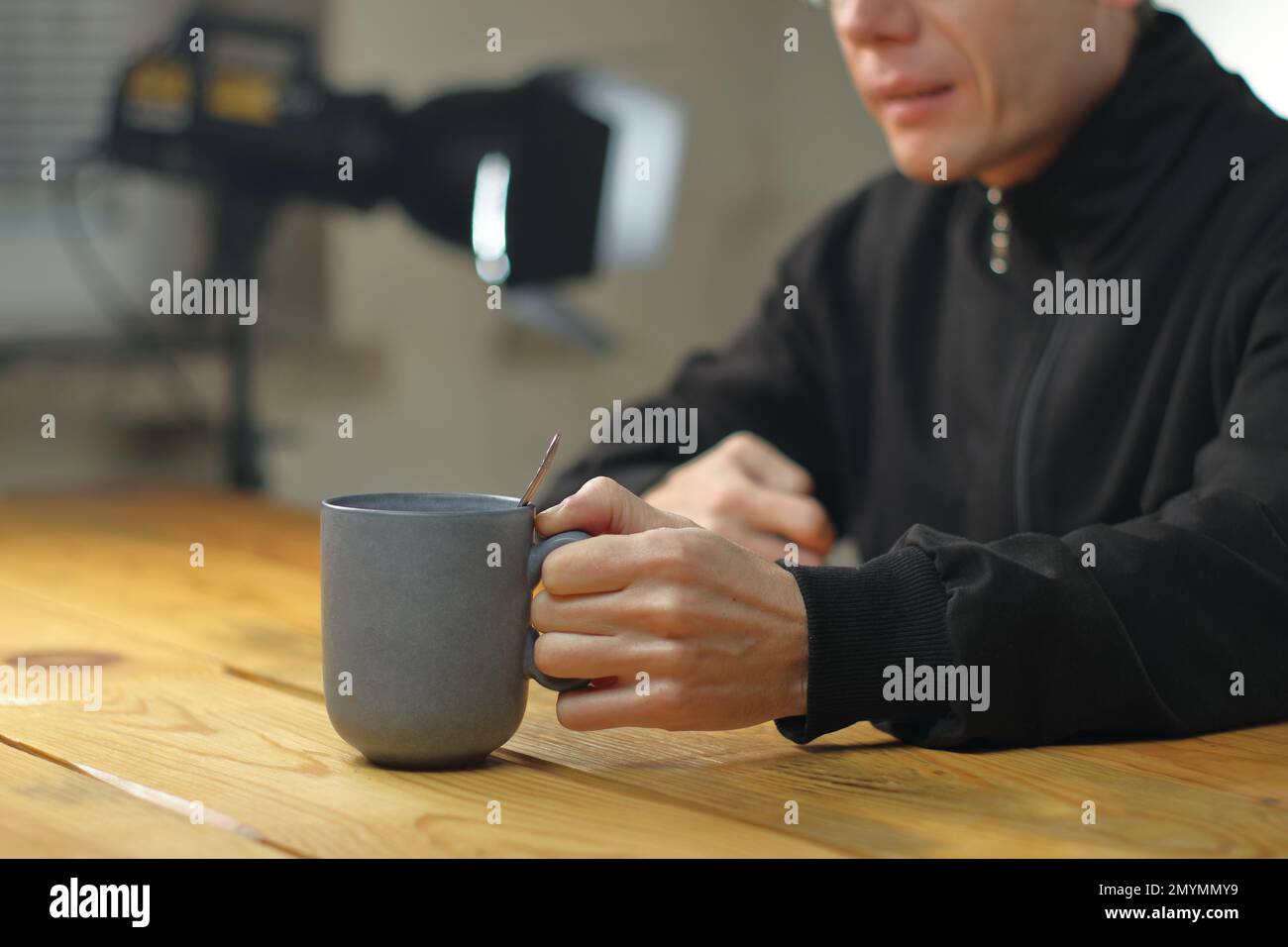 Person, die eine Tasse mit Kaffee vor sich auf dem Tisch hält Stockfoto