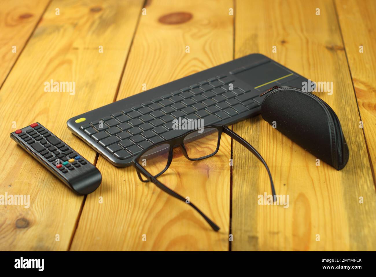Tastatur für fernseher mit Fernbedienung neben Brille und Tasche Stockfoto