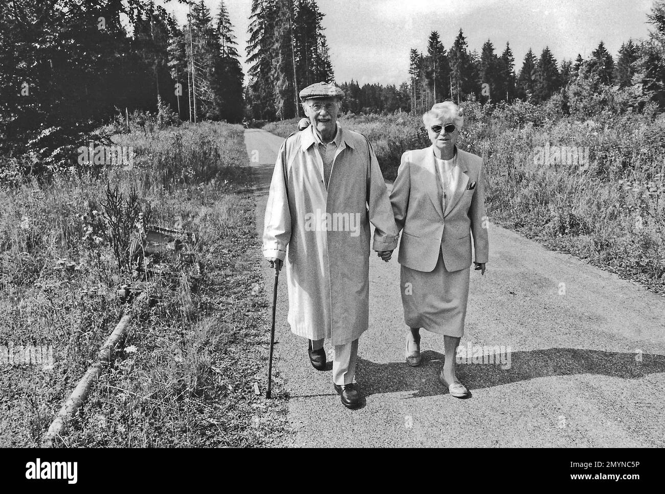 Altes Paar, das Hand in Hand auf dem Waldweg läuft, Grünwald, Bayern, Deutschland, Europa Stockfoto