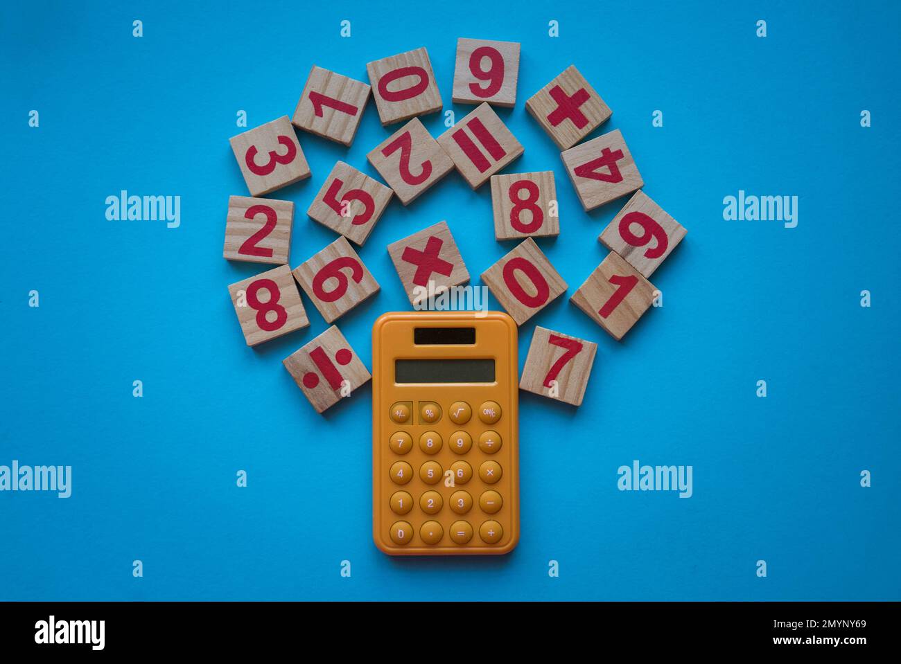 Taschenrechner und eine hölzerne Zahl und ein mathematisches Symbol auf blauem Hintergrund. Stockfoto
