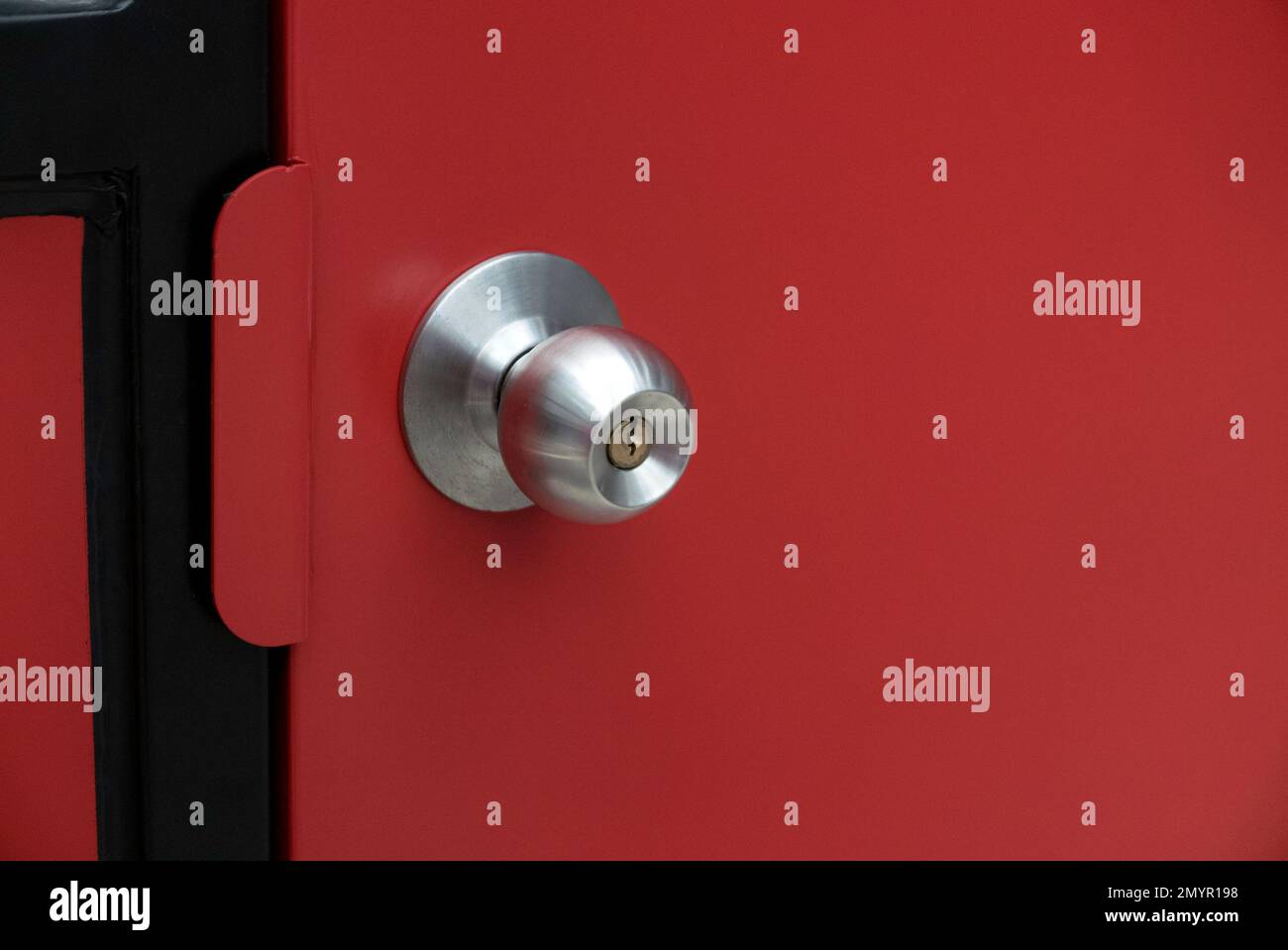 Rote Stahltür mit Türknauf aus Edelstahl. Stockfoto