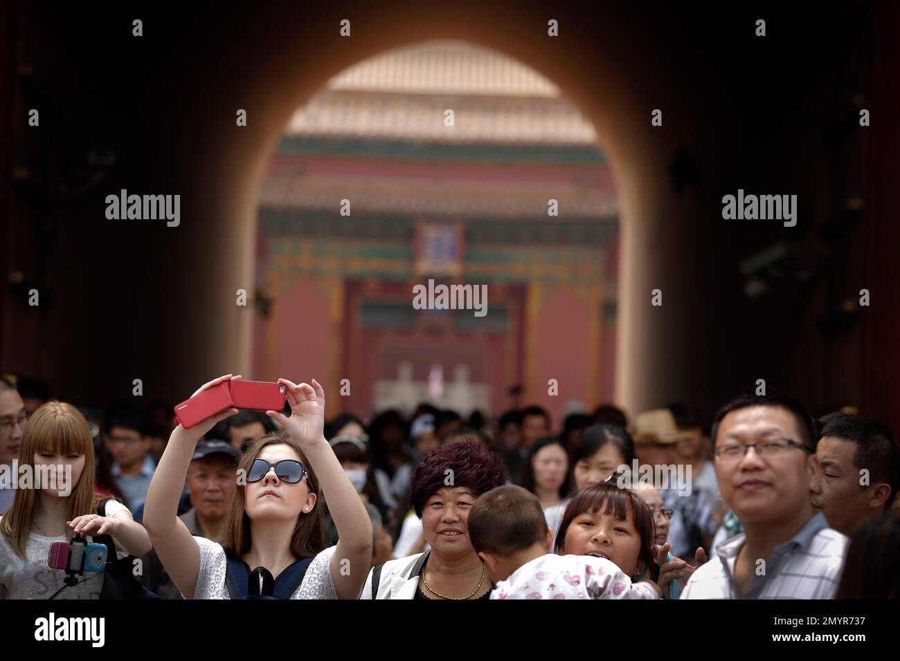 A woman takes a smartphone photo as visitors leave the Forbidden City during the May Day holiday in Beijing, Sunday, May 1, 2016. Millions of Chinese are taking advantage of the May Day holidays to visit popular tourist sites. (AP Photo/Andy Wong) Stockfoto