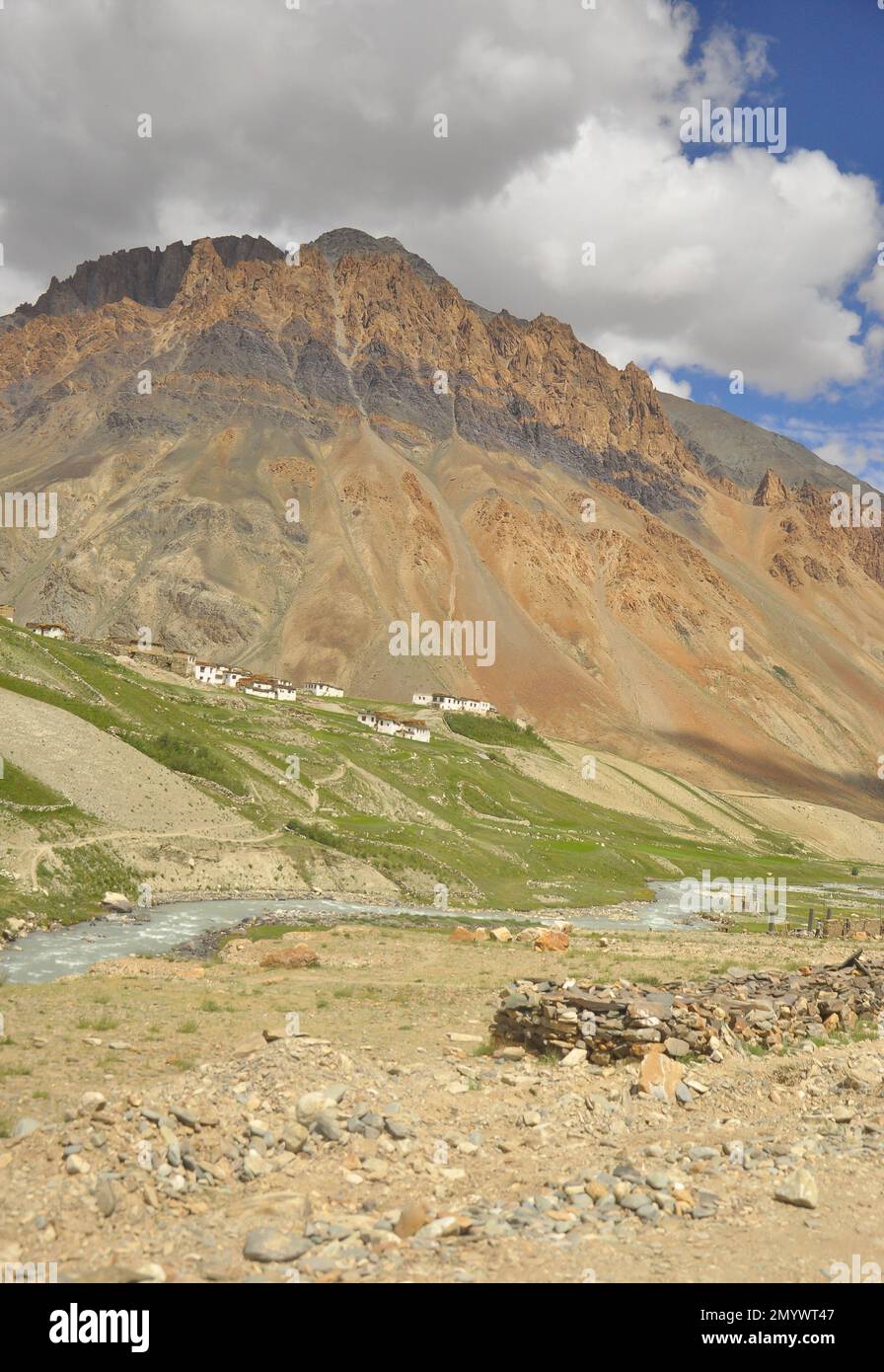 Blick auf ein Dorf neben einem wunderschönen felsigen Berg mit einem Fluss entlang der Darcha-Padum Straße, Ladakh, INDIEN. Stockfoto