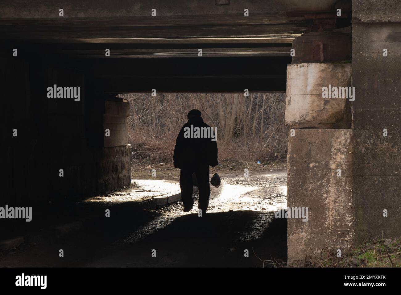 Silhouette eines Mannes, der unter einer Eisenbahnbrücke vorbeifährt Stockfoto
