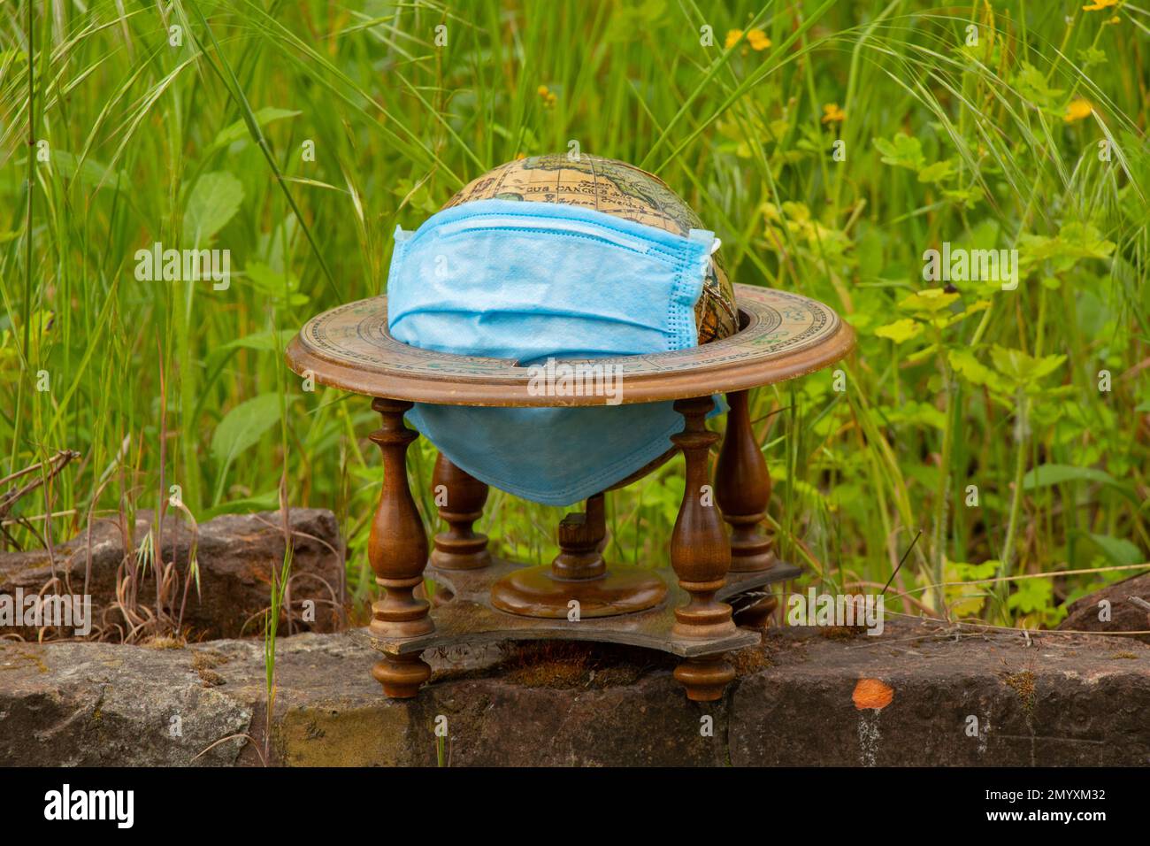 Planet Globus und medizinische Maske liegen während einer Pandemie auf dem Gras auf der Straße Stockfoto Planet Globus und medizinische Maske liegen während einer Pandemie auf dem Gras auf der Straße Stockfoto