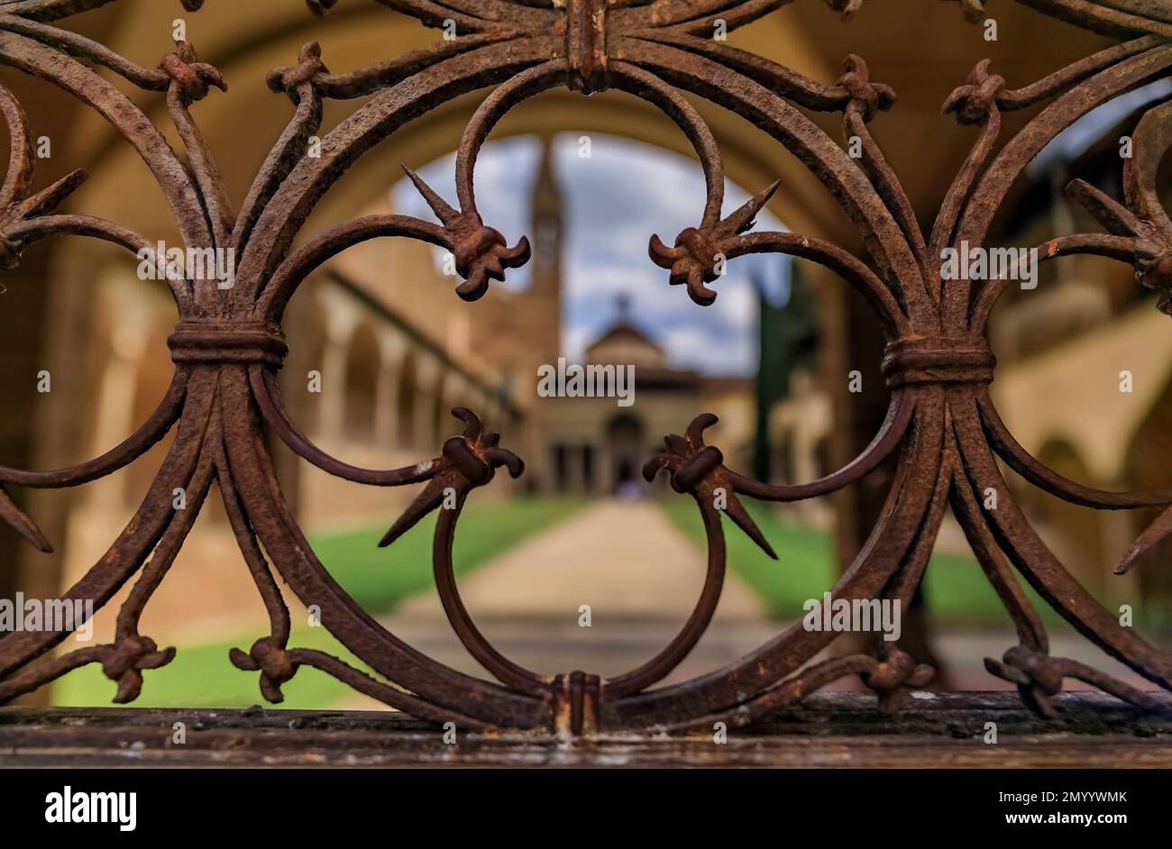 Gärten, Kloster und die Pazzi-Kapelle der Basilika Santa Croce in Florenz in der Toskana, Italien, durch verzierte Metallarbeiten am Eingangstor zu sehen Stockfoto