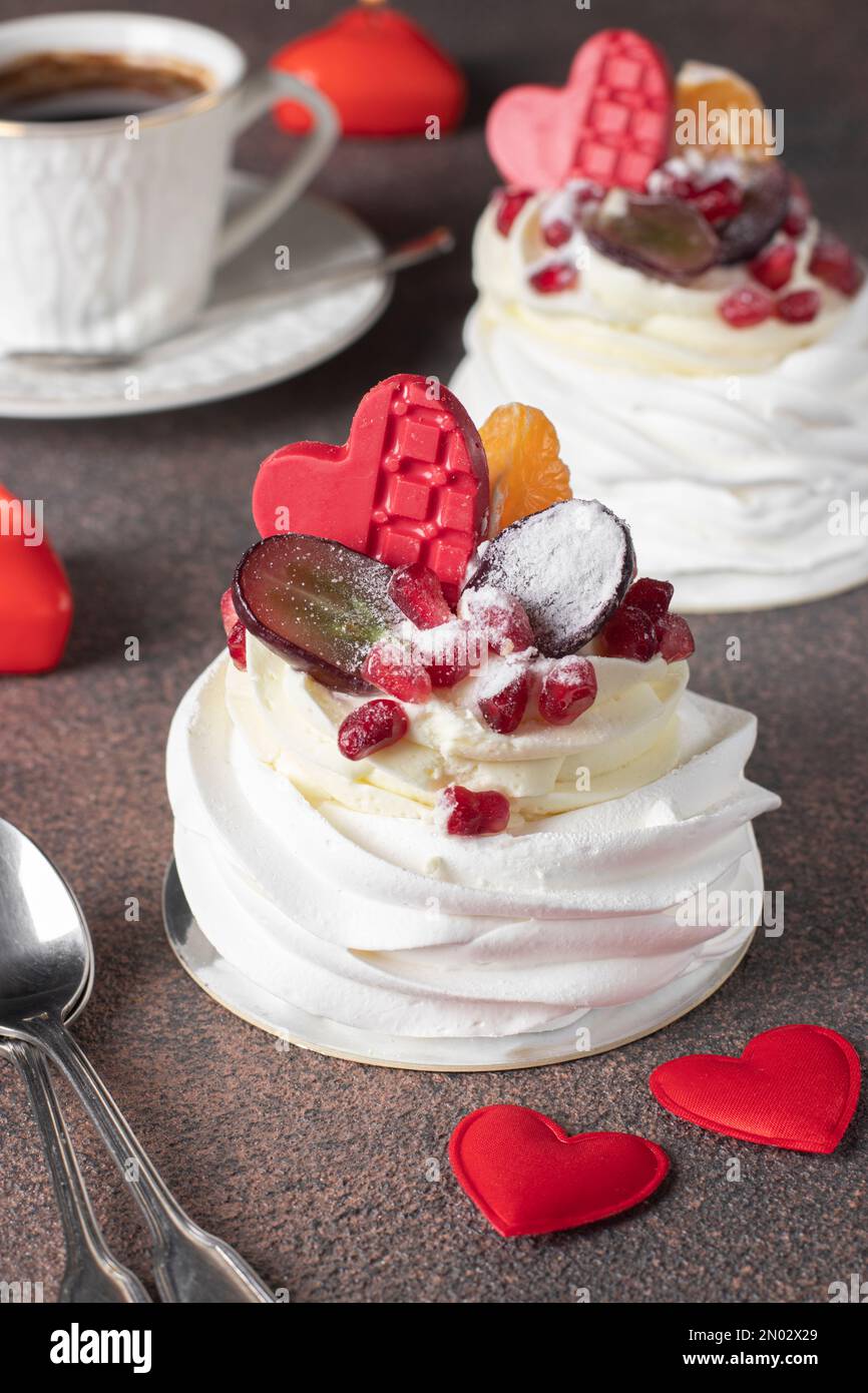 Mini-Pavlova-Kuchen mit Granatapfel, Mandarinen, Trauben und sowie eine Tasse Kaffee, köstliches Dessert zum Valentinstag Stockfoto