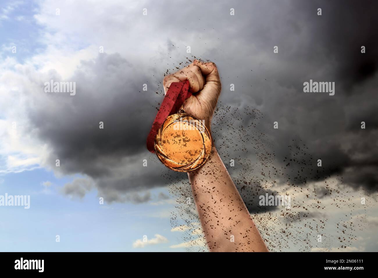 Der Sieger hebt die Hand mit einer Goldmedaille durch den Dreck bis zum Himmel, Nahaufnahme Stockfoto