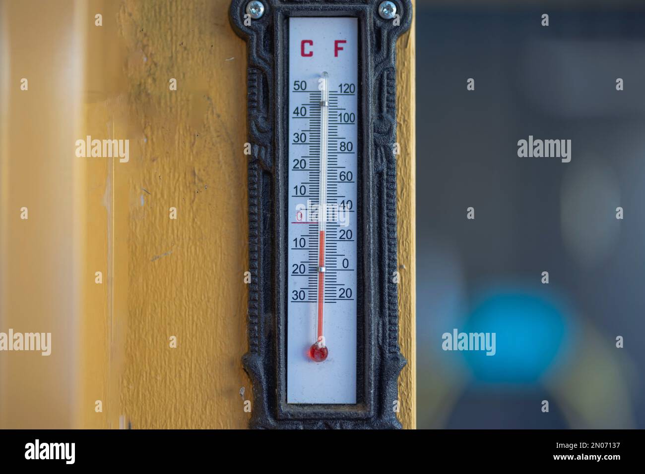 Nahaufnahme des Außenthermometers an der gelben Holzsäule im Winter. Schweden. Stockfoto