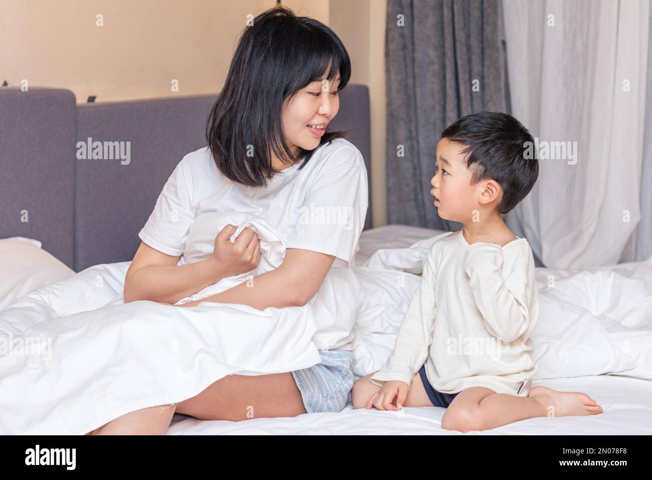 Die Mutter deckte die Decke auf dem Bett, um zu spielen Stockfoto