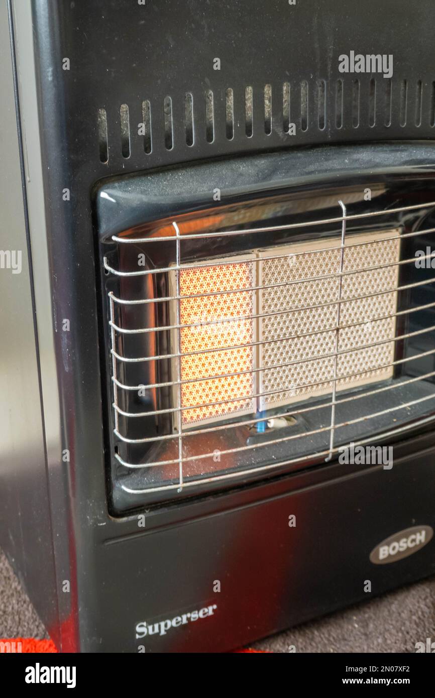 Mobiles Heizgerät, das mit Butangas betrieben wird, wobei ein Teil Wärme in einem Wohnzimmer in Großbritannien abgibt Stockfoto