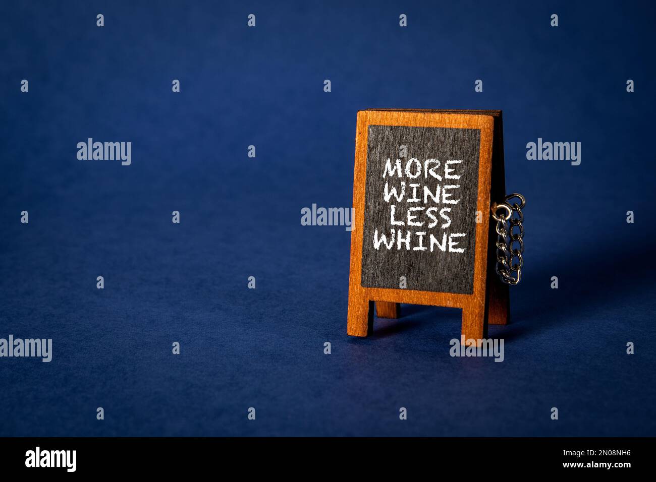 Mehr Wein Weniger Jammern. Miniatur-Tafel auf blauem Hintergrund. Stockfoto