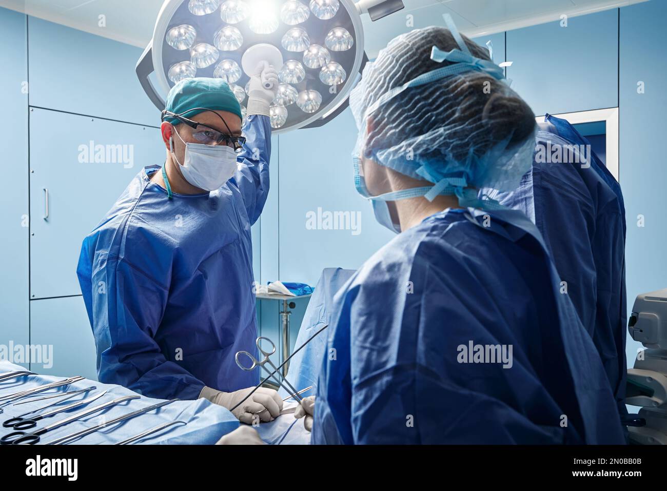 Chirurgen, die am Patienten arbeiten, im modernen Operationssaal des Krankenhauses Stockfoto